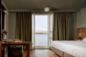 a hotel room with a bed and a large window at Skald Hotel Akureyri, Curio Collection By Hilton in Akureyri +55 photos