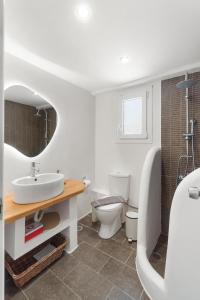 a white bathroom with a sink and a toilet at LausAndros Suites in Andros +18 photos