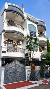a white building with a blue gate and a tree at Moti Manas Mansion - A Homestay in Gwalior in Gwalior