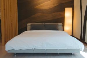 a bedroom with a white bed with a wooden wall at Byeoldeul-ui Gichim Pension in Inje