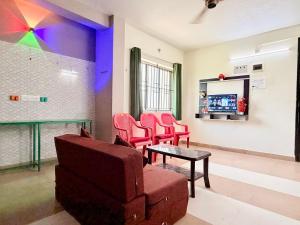 a waiting room with red chairs and a table at Aravind Guest House in Chidambaram
