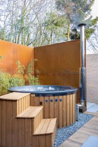 a hot tub in a garden with two wooden benches at Osé in Chênet