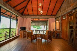 ein Wohnzimmer mit Tisch, Stühlen und Fenstern in der Unterkunft Tea Cottage Resort - Nawalapitiya in Kandy