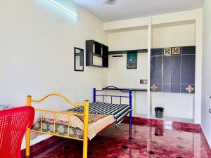 a small room with a bed and a red chair at Aravind Guest House in Chidambaram