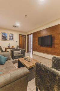 a living room with a couch and a tv on a wall at Lacosta Hotel in Aqaba