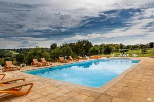a large swimming pool with lounge chairs at Gite Four De Mon Père in Salignac Eyvigues