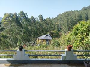 a white fence with a house in the background at Grace villa Homestay in Vattavada +8 photos