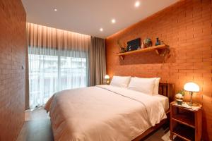 a bedroom with a large bed and a brick wall at Easterly Room 01 in Chanthaburi