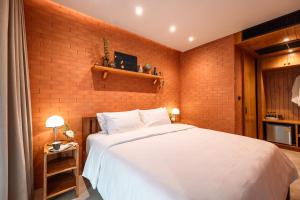 a bedroom with a white bed and a brick wall at Easterly Room 01 in Chanthaburi +6 photos