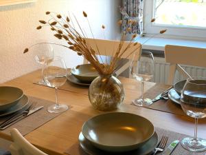 a table with plates and glasses and a vase on it at Dat Lüttje in Fehmarn