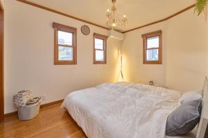a bedroom with a bed with a chandelier and windows at Villa上条 名古屋から30分本格ガスグリルでBBQができる宿 in Kasugai +28 photos