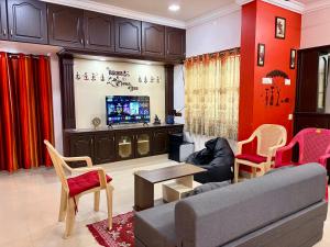 a living room with a couch and chairs and a tv at Royal Paradise Inn in Chidambaram