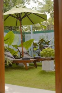 two lounge chairs and an umbrella in the grass at Hide Boutique Villas in Weligama