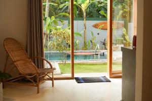 a room with a chair and a sliding glass door at Hide Boutique Villas in Weligama