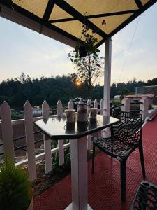 a white table and chairs on a patio with a view at Rosewood Camellia - Near Ooty Town in Ooty +15 photos