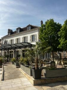 a large white building with chairs and trees in front of it at La maison des Graviers in Nogent-sur-Seine