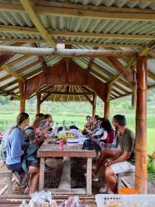 a group of people sitting around a picnic table at SKY SUNSET Bungalows in Tetebatu