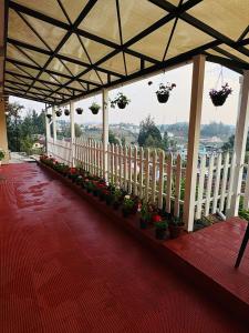 a porch with potted plants and a white fence at Rosewood Camellia - Near Ooty Town in Ooty