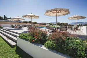 a patio with chairs and umbrellas and a pool at Nassau Guest Farm in Stellenbosch
