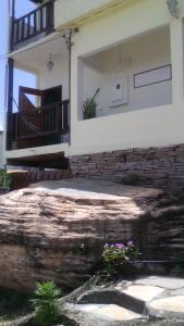 a house with a large rock and flowers in front of it at Pousada da Toca in São Thomé das Letras