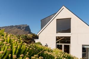a white house with a mountain in the background at The Dunes Pringle Bay in Pringle Bay