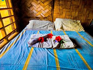 a bed with blue sheets and red flowers on it at Montanna bungalow in Lénakel