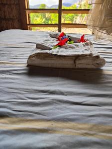 a bed with two red flowers on top of it at Montanna bungalow in Lénakel