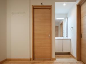 a wooden door in a bathroom with a sink at マークヴィラ松本 in Matsumoto