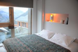 a bedroom with a bed and a large window at Home by U - Chalet 5 in Saint-Martin-de-Belleville