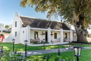 a white house with a tree and lights at Nassau Guest Farm in Stellenbosch
