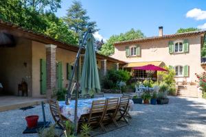 a patio with a table with an umbrella and chairs at Bastide Du Maoupas Gîtes in Belgentier