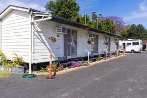 a small white house with a porch and flowers at Rivergums Caravan Park in Goondiwindi