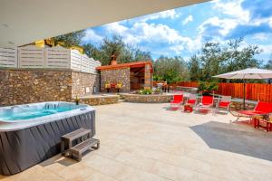 a patio with a hot tub and a table and chairs at Villa Hemera - Mediterranean elegance with private jacuzzi and Capri views in Massa Lubrense