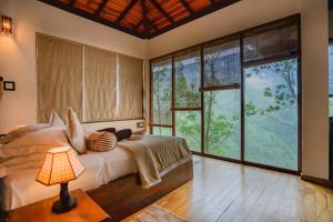 ein Schlafzimmer mit einem großen Bett und großen Fenstern in der Unterkunft Tea Cottage Resort - Nawalapitiya in Kandy + 87 Fotos