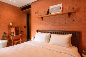 ein Schlafzimmer mit einem Bett vor einer Ziegelwand in der Unterkunft Easterly Room 02 in Chanthaburi