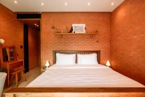 ein Bett in einem Zimmer mit einer Backsteinwand in der Unterkunft Easterly Room 02 in Chanthaburi