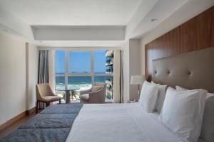 a hotel room with a bed and a view of the ocean at Windsor Marapendi Hotel in Rio de Janeiro