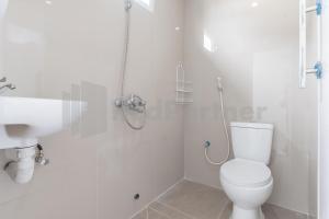 a white bathroom with a toilet and a shower at Adam Guesthouse Mitra RedDoorz in Bogor