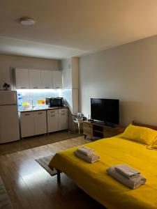 a bedroom with a yellow bed and a kitchen at Unik's Studio Apartment in Prizren