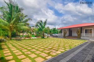 a yard in front of a house with palm trees at EKOSTAY - Simba Villa in Karjat