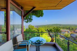 a glass table on a balcony with a view at Ramsukh Resorts and Spa in Mahabaleshwar