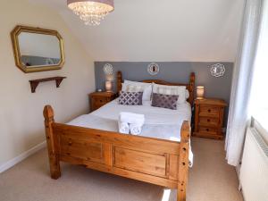 a bedroom with a wooden bed with towels on it at Rosemarie Annexe in Axminster
