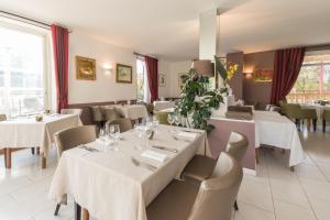 a dining room with white tables and chairs at Logis Hôtel Le Jabron in La Bégude-de-Mazenc