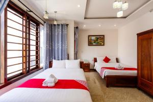 a bedroom with two beds with red and white sheets at Hoi An Legend Connect Villa in Hoi An