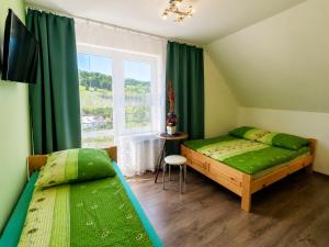 a bedroom with two beds and a window with green curtains at Cichy Potok in Polańczyk