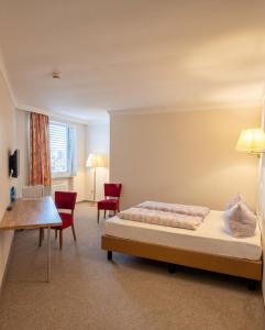 a bedroom with a bed and two red chairs at Hotel Pause - Free WiFi & Free Parking!! in Hofheim am Taunus