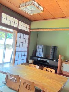 a dining room with a large wooden table and chairs at オリーブママのヤド 凪 バーベキュー機材レンタル可 in Shodoshima