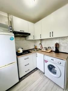 a kitchen with white cabinets and a washer and dryer at Apartment Plaza tower in Shymkent