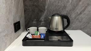 a coffee pot and cups on a tray on a counter at Hotel Bloom Residency in Dehradun