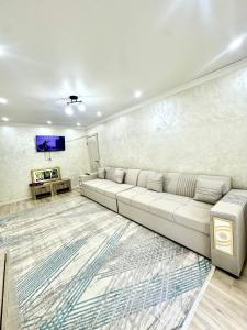 a living room with a white couch and a tv at Apartment Plaza tower in Shymkent